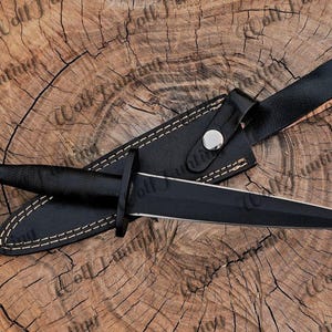 May include: A black dagger with a black leather sheath and a white stitching detail. The dagger has a black handle and a sharp, pointed blade.