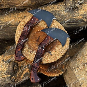 May include: Two hand-crafted axes with wooden handles featuring intricate carvings. The axes have black blades and are displayed on a wooden surface.