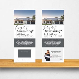May include: Two vertical real estate advertisement displays on a wooden shelf. Each display features a house image and the text "Thinking about Downsizing? I will Guide you every step of the way!" One display includes a realtor's photo and "SOLD" sign.