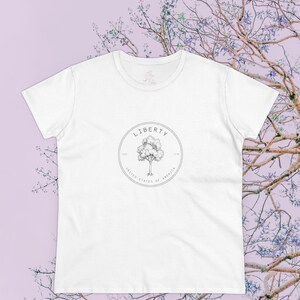 May include: White t-shirt with a black and white graphic of a tree and the text "LIBERTY 1776 UNITED STATES OF AMERICA 1776".