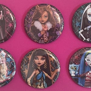May include: A set of six circular pin-back buttons featuring illustrations of various doll characters. Each button displays a unique character with distinct hair, clothing, and accessories against a background of colorful stars and plaid patterns.