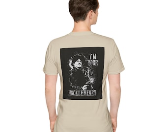 Può includere: Una t-shirt beige con una stampa grafica in bianco e nero di un uomo con un cappello da cowboy. La grafica dice "I'm Your Huckleberry".