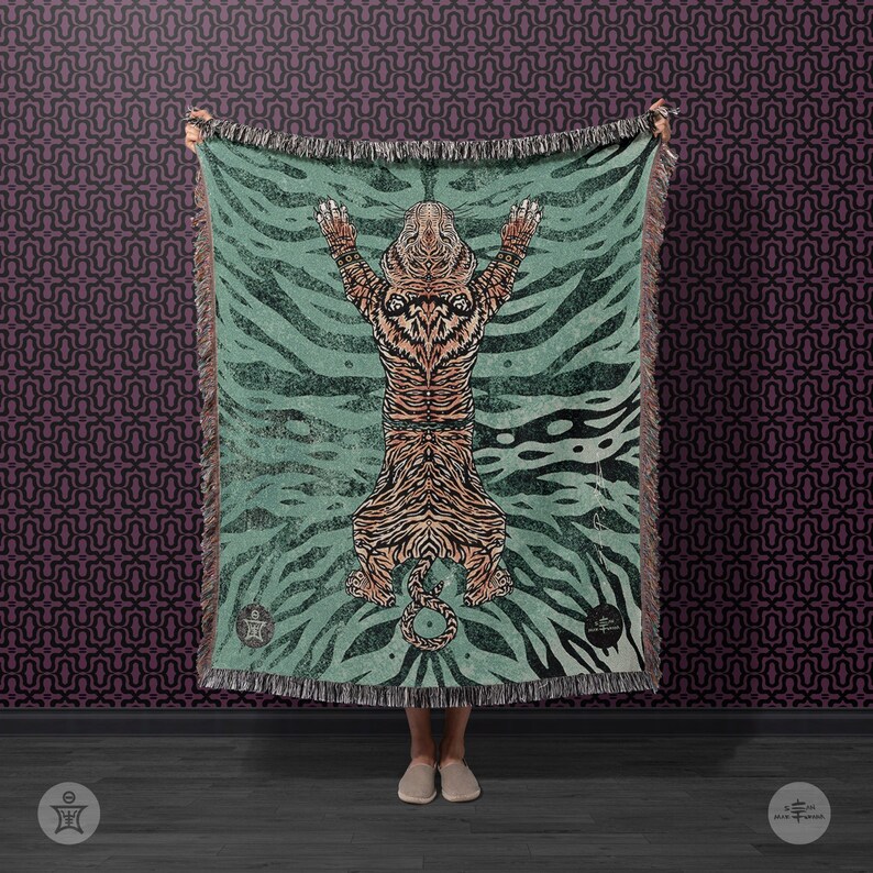 May include: A teal woven throw blanket with a tiger design. The tiger is orange and black with a white belly. The blanket has a fringe border.