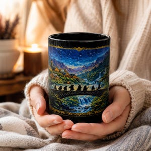 Peut inclure: Un mug en céramique noire orné d'une illustration détaillée et colorée représentant un groupe de petits personnages traversant un pont en pierre vers un village nocturne, sous un ciel étoilé avec montagnes et cascade, encadré de bordures dorées.