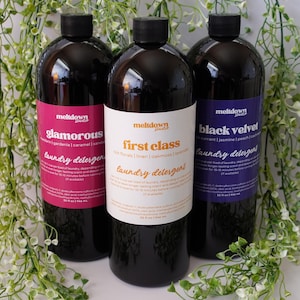 May include: Three bottles of laundry detergent with black tops and colourful labels. The labels read "glamorous", "first class", and "black velvet". Each bottle contains 946 ml of detergent.