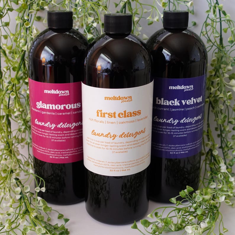 May include: Three bottles of laundry detergent with black tops and colourful labels. The labels read "glamorous", "first class", and "black velvet". Each bottle contains 946 ml of detergent.