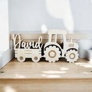 Könnte beinhalten: Aus Holz ausgeschnittenes Modell eines Traktors, der einen Wagen zieht, auf dem der Name "David" steht. Der Traktor und der Wagen sind in natürlicher Holzfarbe lackiert.