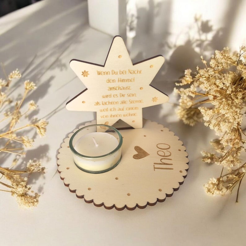 May include: Wooden star-shaped candle holder with a small glass votive candle and the text "Wenn Du bei Nacht den Himmel anschaust wird es Dir sein als lachten alle Sterne weil ich auf einem von ihnen schine" and the name "Theo" on the base.