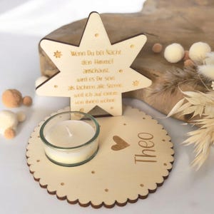May include: Wooden star-shaped candle holder with a quote about stars and a heart with the name Theo. The holder has a small glass votive candle.