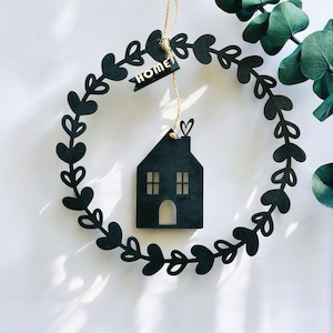 Peut inclure: Guirlande en bois noir avec une découpe de maison et le mot "HOME" sur une bannière. La guirlande est faite de feuilles et de cœurs.