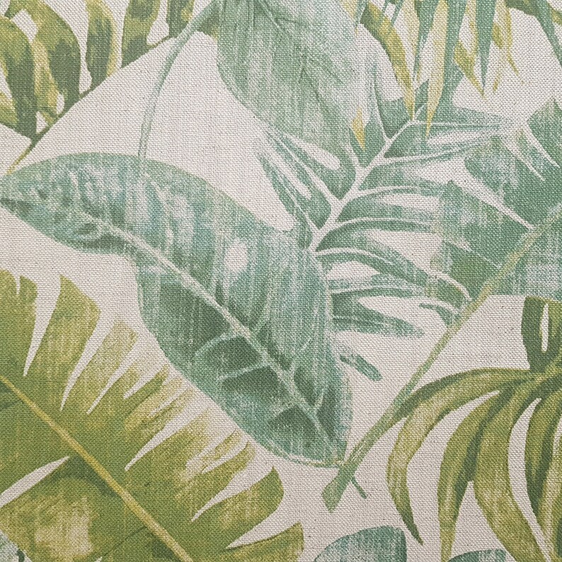 May include: A close-up of a fabric with a green and white tropical leaf pattern. The fabric has a textured surface.