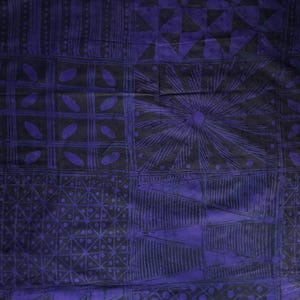 May include: A close-up of a fabric with a repeating geometric pattern in shades of purple and black. The design includes squares, triangles, and sunburst shapes. The fabric appears to be textured.