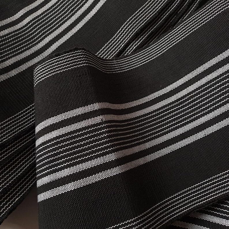 May include: Black and white striped fabric with a woven texture. The fabric is folded and shows the pattern.