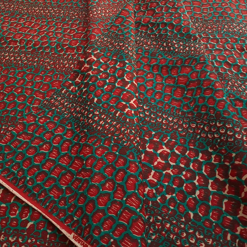 May include: Red and teal fabric with a repeating pattern of small, overlapping circles. The fabric has a subtle sheen and a soft texture.