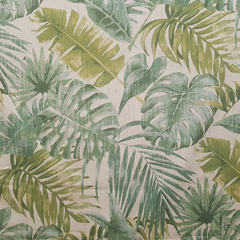May include: A fabric with a tropical leaf pattern in shades of green on a beige background.