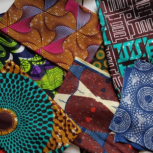 May include: A selection of vibrant African wax print fabrics. The textiles display diverse geometric and abstract patterns in shades of brown, teal, pink, and blue. The fabrics are arranged in a layered composition.