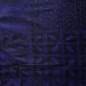 May include: A close-up of a fabric with a dark blue and black geometric pattern. The design includes squares, lines, and oval shapes. The fabric has a textured appearance and a dark color palette.