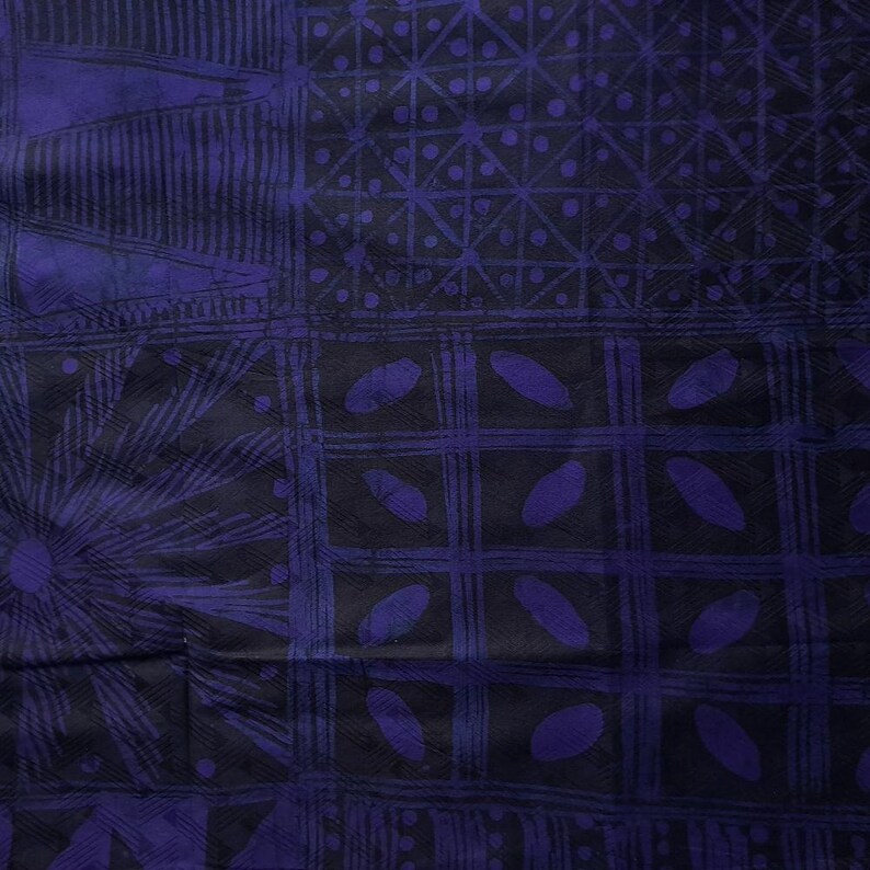 May include: A close-up of a fabric with a dark blue and black geometric pattern. The design includes squares, lines, and oval shapes. The fabric has a textured appearance and a dark color palette.