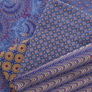 May include: A close-up of three different fabric patterns. The first pattern is a blue and gold paisley design. The second pattern is a blue and red geometric design with small circles. The third pattern is a blue and red wavy design.