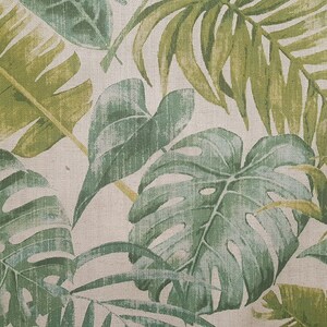 May include: A close-up of a fabric with a tropical leaf pattern. The leaves are green and yellow and have a textured look.