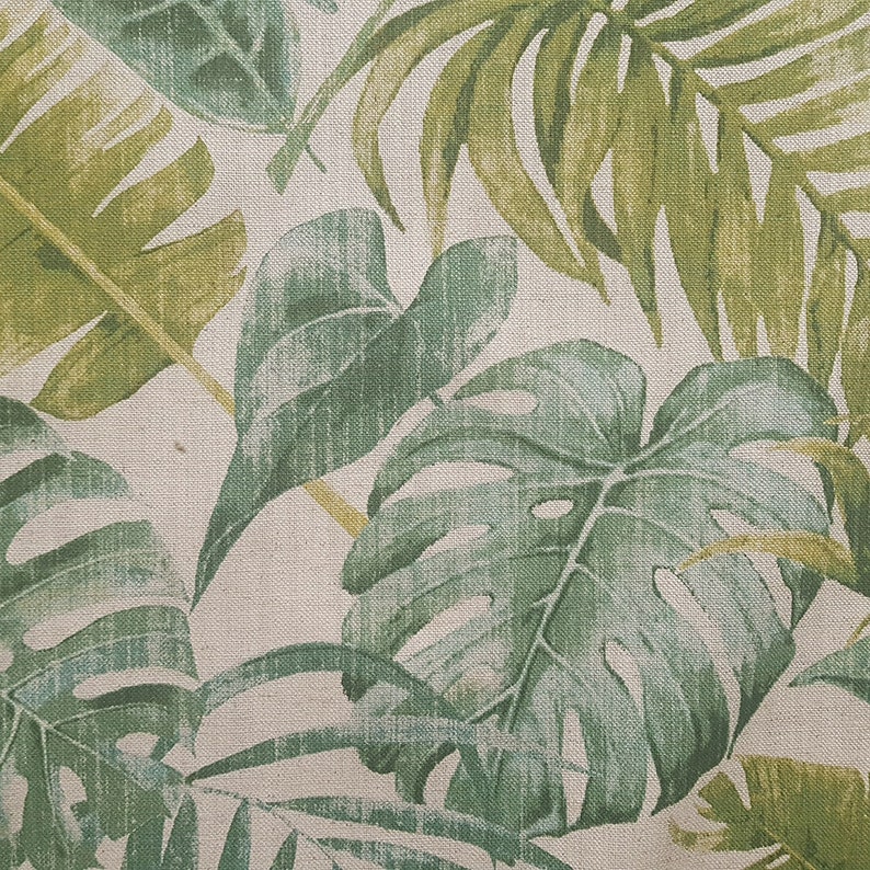 May include: A close-up of a fabric with a tropical leaf pattern. The leaves are green and yellow and have a textured look.