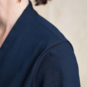 May include: Close-up of the shoulder seam of a navy blue shirt. The fabric is smooth and has a subtle texture.