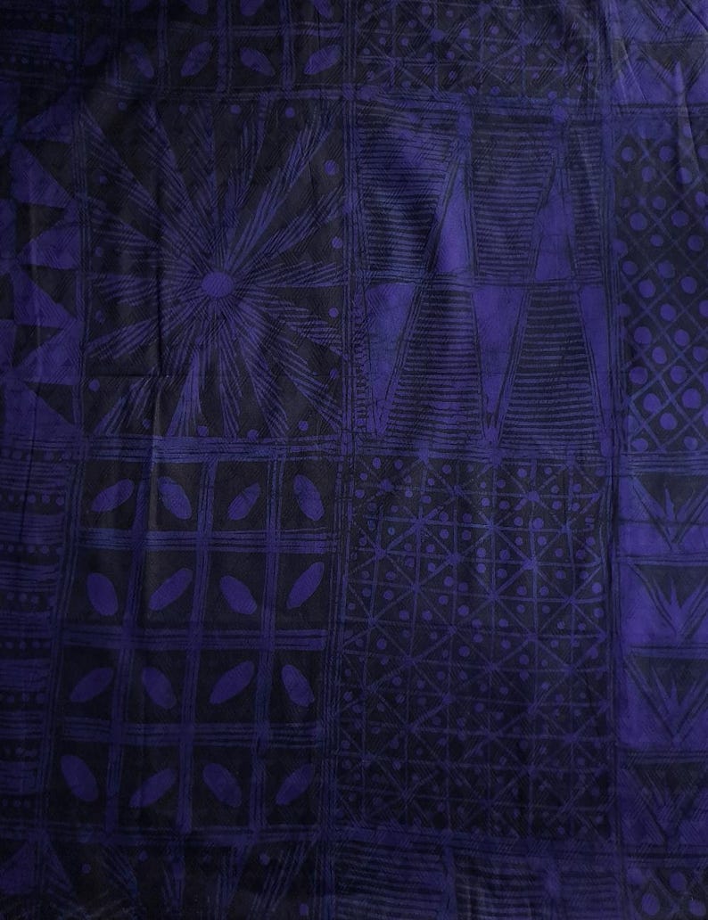 May include: A close-up of a fabric with a repeating geometric pattern in shades of dark blue and black. The design includes squares, triangles, and circular shapes, creating a textured appearance. The fabric has a slightly wrinkled texture.