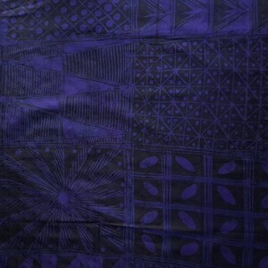 May include: A close-up of a textile with a geometric pattern in shades of black and purple. The design features squares, triangles, and other shapes. The fabric has a textured appearance.