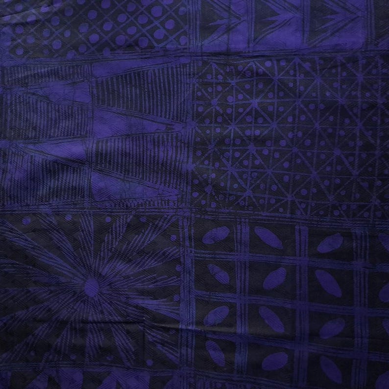 May include: A close-up of a textile with a geometric pattern in shades of black and purple. The design features squares, triangles, and other shapes. The fabric has a textured appearance.