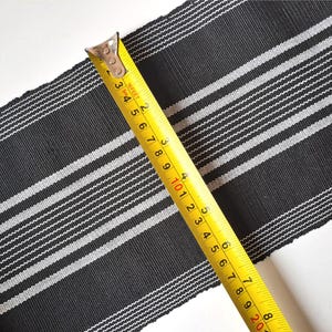 May include: Black and white striped fabric with a yellow measuring tape. The tape reads 16 feet and 2 inches.