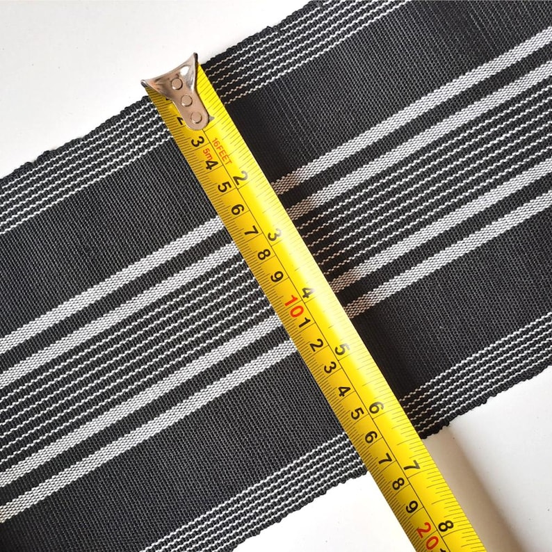 May include: Black and white striped fabric with a yellow measuring tape. The tape reads 16 feet and 2 inches.