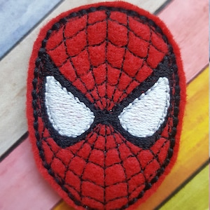 May include: Red felt applique of a superhero mask with a black web design and white eyes.