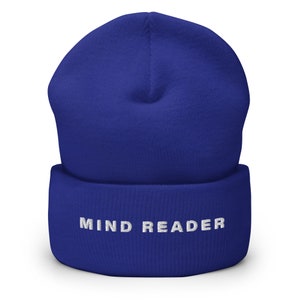 Pode incluir: Um gorro azul royal com o texto bordado "MIND READER" em branco. O chapéu é feito de um material de malha macia e tem uma bainha dobrada. Este acessório de inverno é elegante.