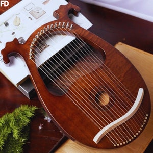 Puede incluir: Un laúd de madera marrón con cuerdas doradas y una tapa armónica blanca. El laúd tiene un diseño decorativo en la tapa armónica.