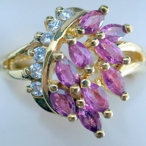 May include: A gold ring with a cluster of marquise-shaped pink gemstones and smaller round white gemstones.