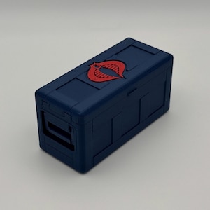 May include: A blue plastic storage box with a red Cobra logo on the top. The box has a hinged lid and a latch.