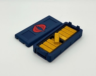 May include: A blue rectangular container with a red emblem on the lid, open to reveal several gold-colored rectangular bars. The bars are arranged inside the container. The lid is placed to the side.