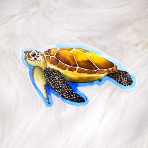May include: A watercolor illustration of a sea turtle swimming in blue water. The turtle has a brown shell with yellow markings and black flippers.