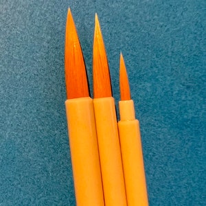 May include: Three paint brushes with wooden handles and natural bristles. The brushes are different sizes, with the largest brush on the left and the smallest brush on the right.