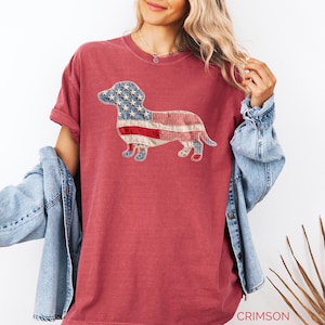 Crimson Comfort Colors patriotic dachshund patchwork t-shirt for women, featuring a large quilted wiener dog graphic with embroidered white stars, denim blue, red gingham, cream floral, and striped fabric — 4th of July dachshund mom gift, American flag wiener dog tee, cute dog mom patriotic shirt, patchwork dachshund Comfort Colors tee, dachshund lover gift idea.