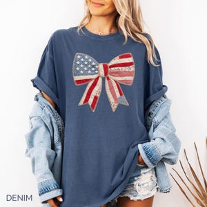 Ivory Comfort Colors patriotic bow patchwork t-shirt for women, featuring a large quilted bow graphic with embroidered white stars, red gingham, cream floral, and striped fabric — coquette 4th of July gift idea, American flag bow tee, cute patriotic shirt women, patchwork bow Comfort Colors shirt.