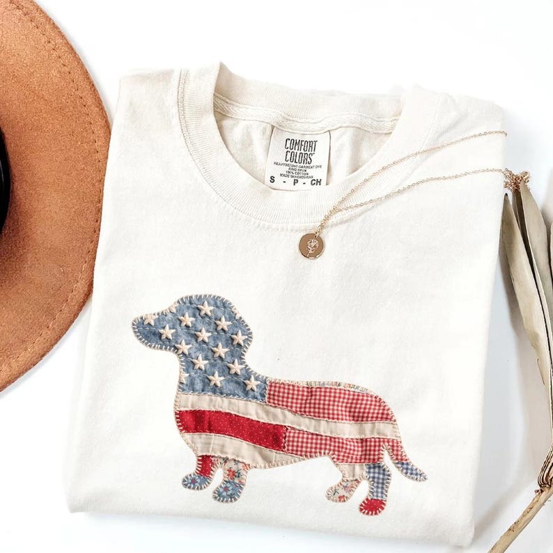 Ivory Comfort Colors patriotic dachshund patchwork t-shirt for women, featuring a large quilted wiener dog graphic with embroidered white stars, denim blue, red gingham, cream floral, and striped fabric — 4th of July dachshund mom gift, American flag wiener dog tee, cute dog mom patriotic shirt, patchwork dachshund Comfort Colors tee, dachshund lover gift idea.