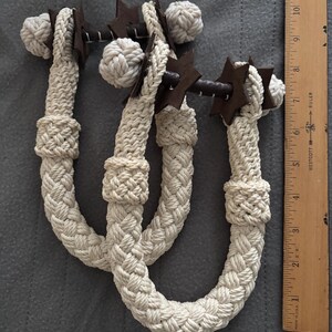May include: Three cream-colored rope horse reins with brown star-shaped accents and metal hardware. A wooden ruler is placed next to the reins. The reins are approximately 30 inches long.