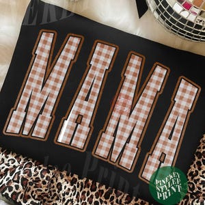 May include: A black sweatshirt featuring the word MAMA in large, block-style letters. The letters have a brown and white gingham checkered pattern with a thin brown outline. The design is centered on the front of the garment.