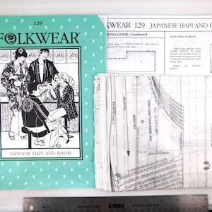 May include: A Folkwear 129 Japanese Hapi and Haori sewing pattern set with a teal cover featuring a black and white illustration of people in traditional garments, accompanied by printed instruction pages and translucent pattern tissue paper.
