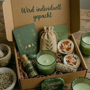 Könnte beinhalten: Eine Pappschachtel mit der Aufschrift Wird individuell gepackt, enthaltend eine grüne Karte mit Mondphasen, einen Jutebeutel, ein Kräuterfläschchen, zwei Kerzen mit getrockneten Früchten, ein Salbeibündel und eine grüne Steinplatte Spirituelle Box.