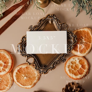 May include: A rectangular white card with the text 3.5X5" printed on it, resting on an ornate bronze-colored metal tray. The scene is decorated with dried orange slices, pinecones, evergreen sprigs, and brown velvet ribbon.