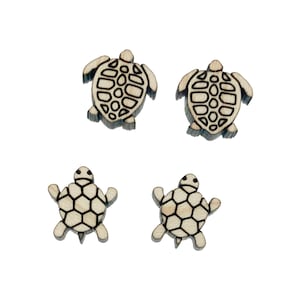 May include: Four wooden turtle-shaped earrings. Two pairs of earrings are visible, each with a different design. The turtles have a light wood color with dark brown etched details. The earrings are on a white background.