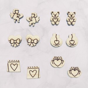 May include: Set of 10 wooden earrings with various Valentine's Day themes, including angels, bears, hearts, and hands holding hearts.