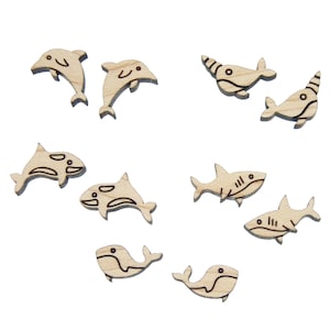 May include: A set of wooden sea creature shapes, including dolphins, whales, sharks, and narwhals. The shapes are cut out of light brown wood and have black outlines.